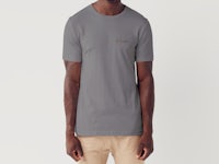 a man wearing a grey t - shirt with a gold logo